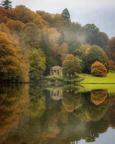 a lake surrounded by trees in the middle of it with a gazebo on top