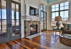 a living room filled with furniture and a fire place in front of two large windows