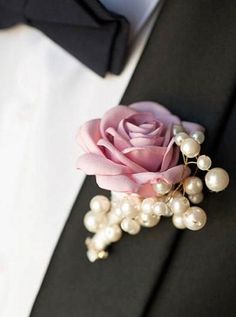 a boutonniere with a pink rose and white pearls on the lapel