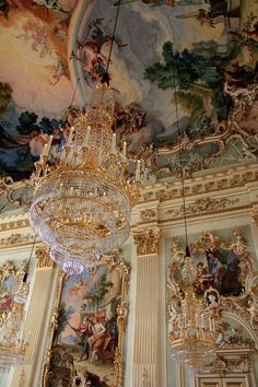 a chandelier hanging from the ceiling in a room with ornate paintings on it