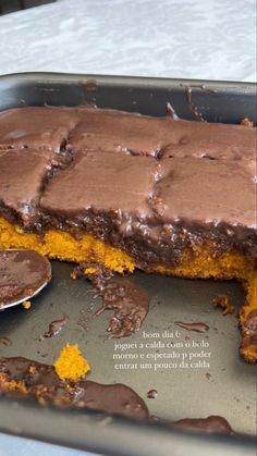 there is a chocolate cake in the pan with a spoon next to it and some pieces missing