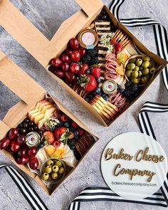 two boxes filled with different types of food on top of a striped table cloth next to each other