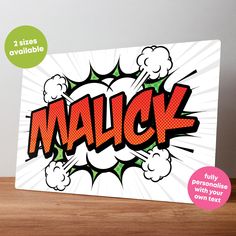 a card with the word malck in comic style pop art on it, sitting on a wooden table