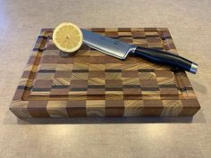 a cutting board with a knife on top of it next to a slice of lemon