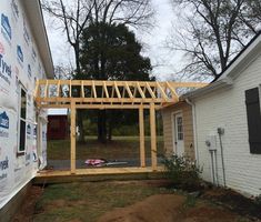 a house being built in the middle of a yard with wood framing and siding on it