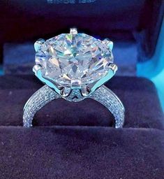 a diamond ring sitting on top of a black velvet box with its reflection in it