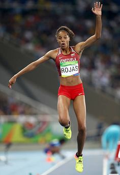 a woman jumping in the air on top of a track