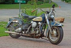 an old motorcycle is parked on the side of the road in front of a street sign