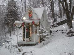 a white house covered in snow with christmas decorations on the front porch and wreaths hanging from the windows