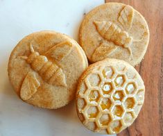 three cookies with bees carved into them on a table