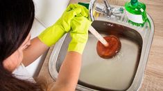 a woman washing her hands in a sink with soap and cleaning products on the side