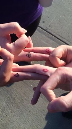 four people are holding their hands together with small tattoos on them