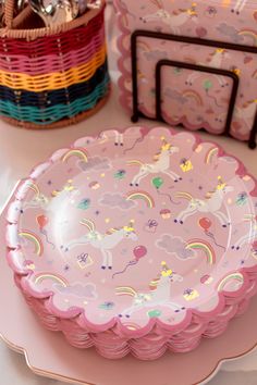 there is a pink plate with unicorns on it next to other plates and baskets