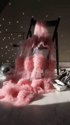 a chair with pink ruffles on the floor next to high heeled shoes