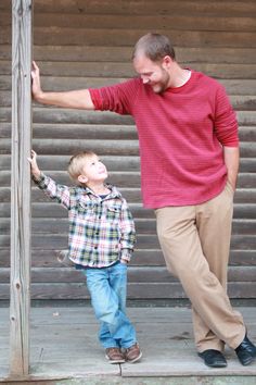 a man standing next to a little boy on top of a wooden step holding his hand up