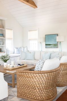 a living room filled with white furniture and lots of pillows on top of the couches