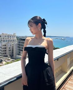 a woman standing on top of a balcony next to the ocean