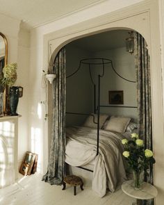 a bedroom with a canopy bed and flowers in vases on the floor next to it