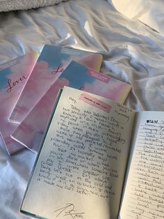 an open book sitting on top of a bed next to three other books with writing on them