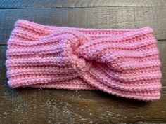 a pink knitted headband laying on top of a wooden floor