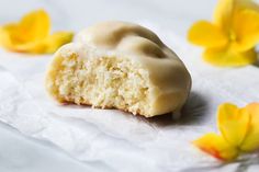 a half eaten doughnut sitting on top of a piece of paper next to yellow flowers