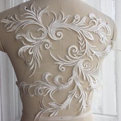 the back of a woman's dress with white embroiderys on it and an intricate design