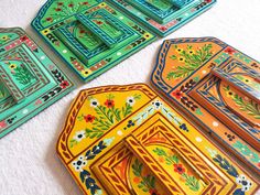 colorful plates and trays are laid out on a tableclothed surface, with designs painted on them