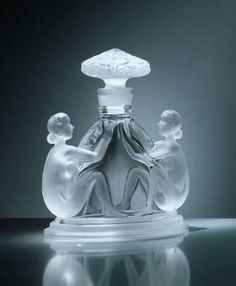 a glass perfume bottle sitting on top of a table next to a black and white background