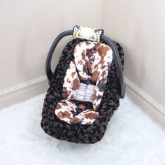 a brown and white cow print car seat cover sitting on top of a fluffy rug