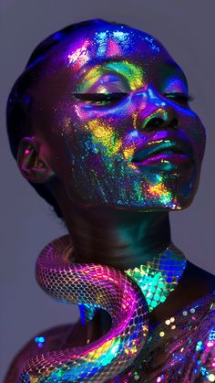 a woman with her face covered in holographic paint and holding a snake around her neck