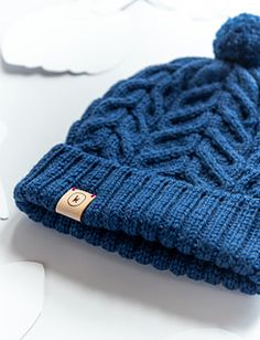 a blue knitted hat sitting on top of a white table next to cut outs