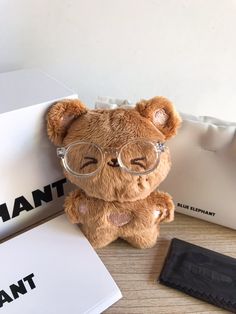 a brown teddy bear wearing glasses next to a white box