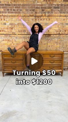 a woman sitting on top of a dresser with her arms spread out in the air