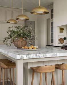 a kitchen with marble counter tops and gold pendant lights hanging from the ceiling above it