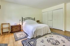 a bedroom with a bed, rug and two nightstands on the hardwood flooring