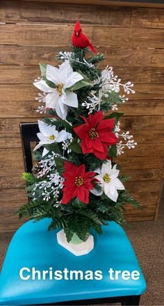 a christmas tree decorated with poinsettis and greenery on a blue chair