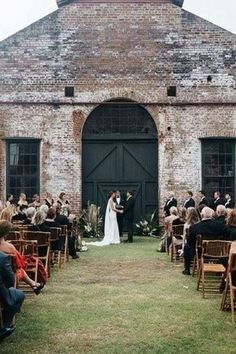 a bride and groom standing in front of an old brick building at their wedding ceremony