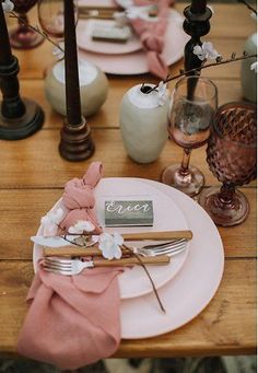 the table is set with pink napkins and place settings for an elegant dinner party