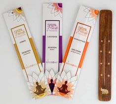 three incense sticks are sitting next to each other on a white surface with an orange flower