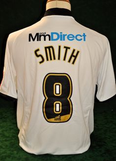 the back of a white shirt with black and gold numbers on it that says,'mmm direct smith 8 '