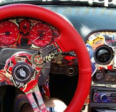 the interior of a car with red steering wheel covers and stickers on it's dashboard