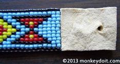 a beaded wristband with an arrow on the front and back side, sitting on a wooden surface