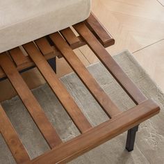 a close up view of a wooden bench with metal legs and seat cushion on the floor