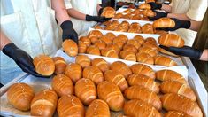 several people in black gloves are making croissants