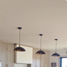 a kitchen with three lights hanging from the ceiling