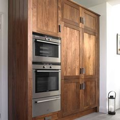 a kitchen with wooden cabinets and stainless steel ovens