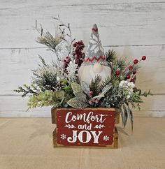 a wooden box filled with christmas decorations and greenery next to a sign that says comfort and joy