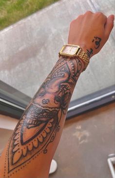 a person's arm with tattoos on it and a watch in the other hand