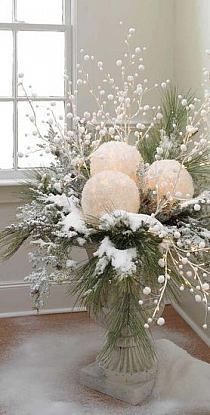 a vase filled with white flowers on top of a wooden floor next to a window