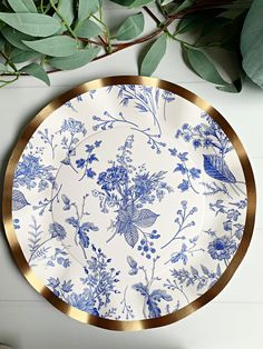 a blue and white plate sitting on top of a table next to green leaves,